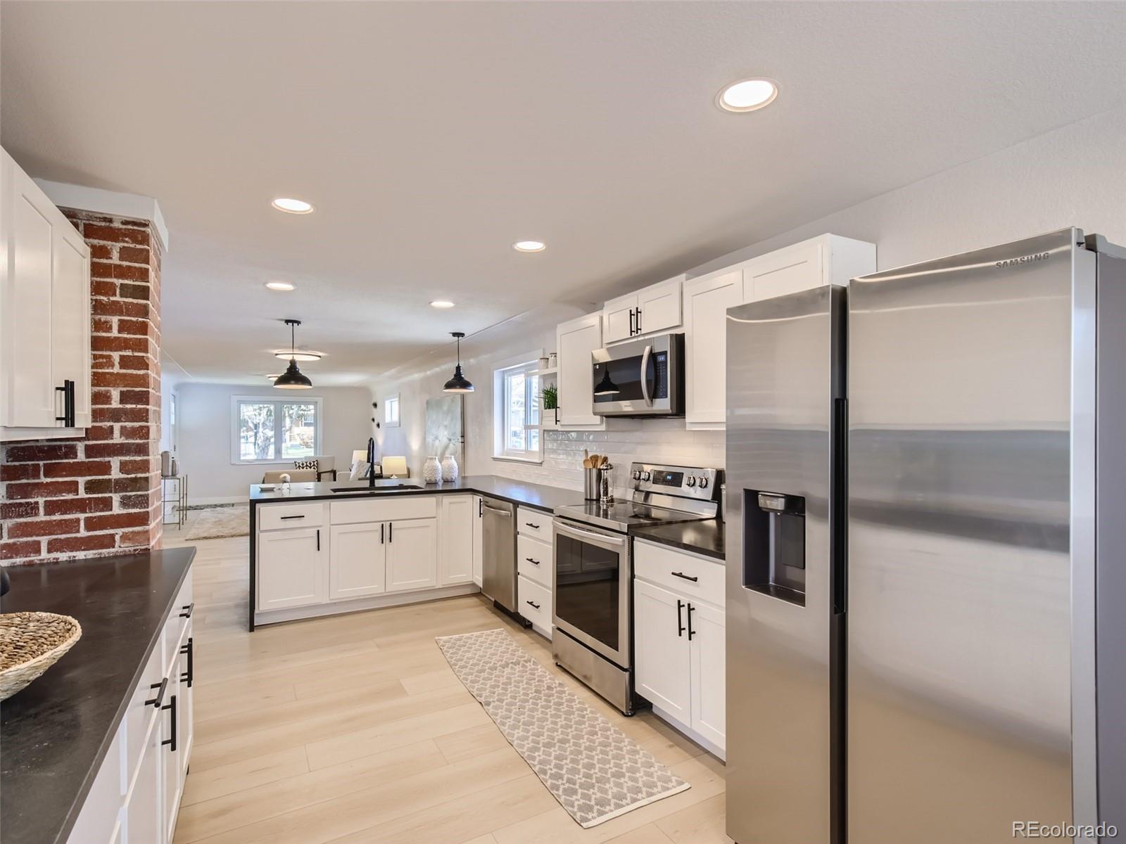 2814 Chase Street Wheat Ridge, CO 80214 - Photo 10 of 28 a large kitchen with stainless steel appliances kitchen island granite countertop a refrigerator a stove a sink dishwasher and white cabinets with wooden floor