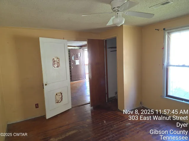 a view of an empty room with a window and wooden floor