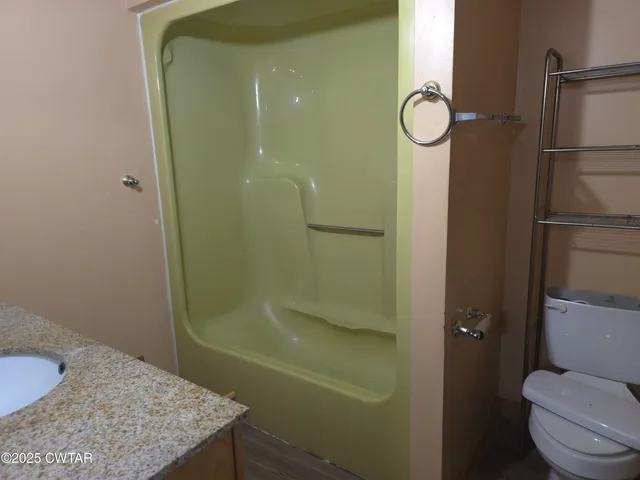 a bathroom with a granite countertop shower a toilet and a sink