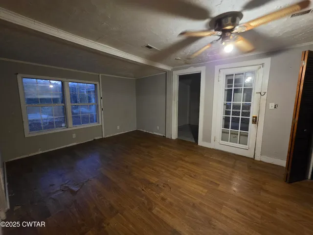 an empty room with wooden floor and windows