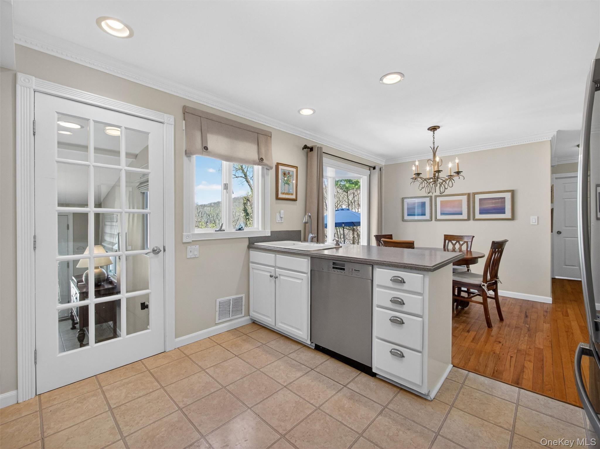 20 Tygert Road Blauvelt, NY 10913 - Photo 13 of 40 Kitchen featuring stainless steel appliances, light tile patterned floors, white cabinetry, ornamental molding, and a chandelier