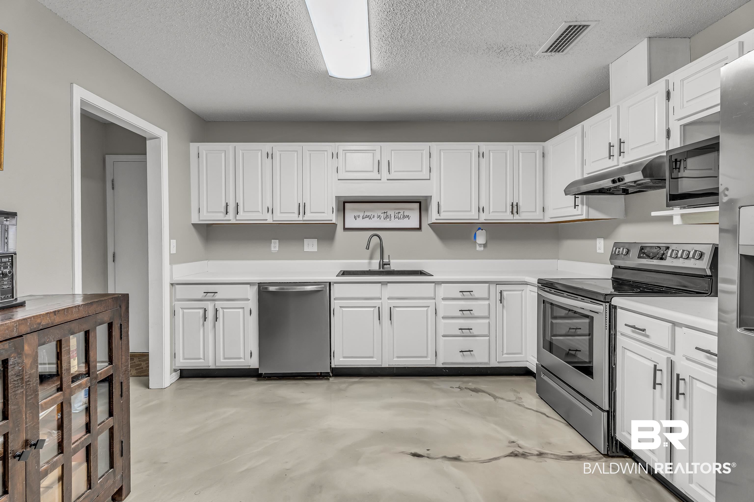 23214 Rochelle Loop Robertsdale, AL 36567 - Photo 18 of 27 Kitchen featuring stainless steel appliances, under cabinet range hood, white cabinetry, light countertops, and a textured ceiling