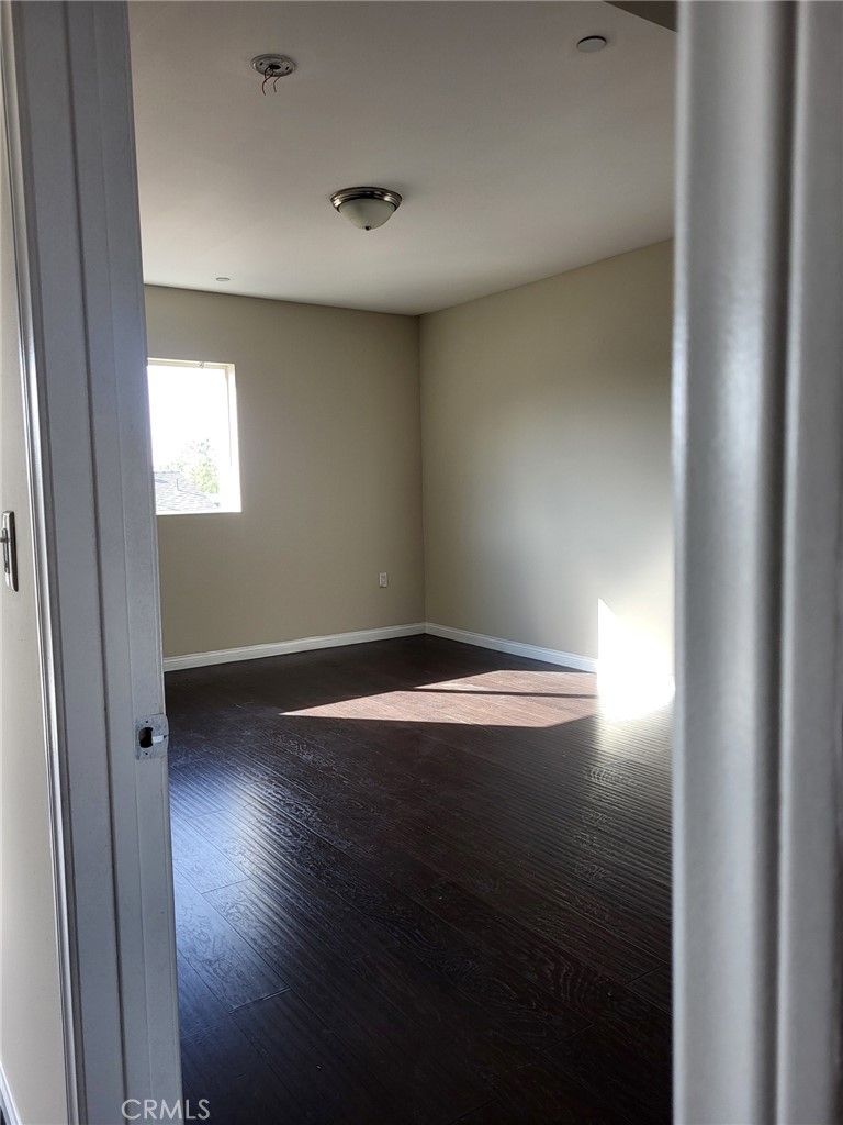 13190 Bromont Avenue, Unit 315 Sylmar, CA 91342 - Photo 7 of 10 an empty room with wooden floor and windows