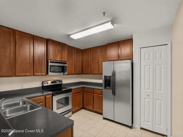 a kitchen with stainless steel appliances granite countertop a refrigerator a sink a stove a microwave and wooden cabinets