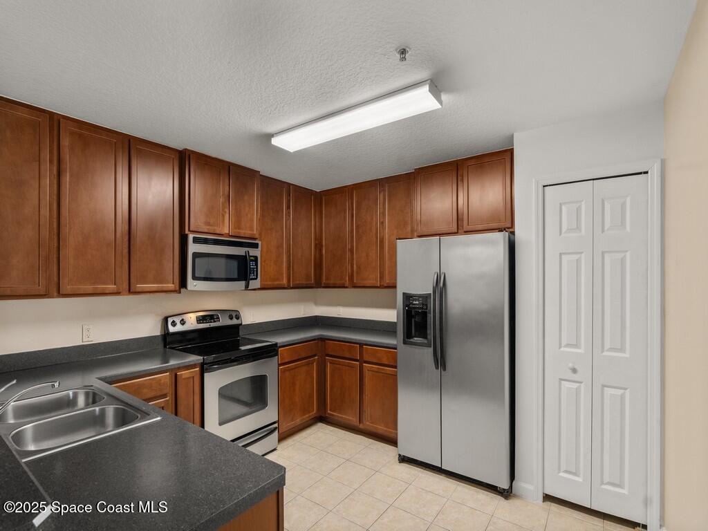 4026 Meander Place, Unit 208 Rockledge, FL 32955 - Photo 11 of 32 a kitchen with stainless steel appliances granite countertop a refrigerator a sink a stove a microwave and wooden cabinets