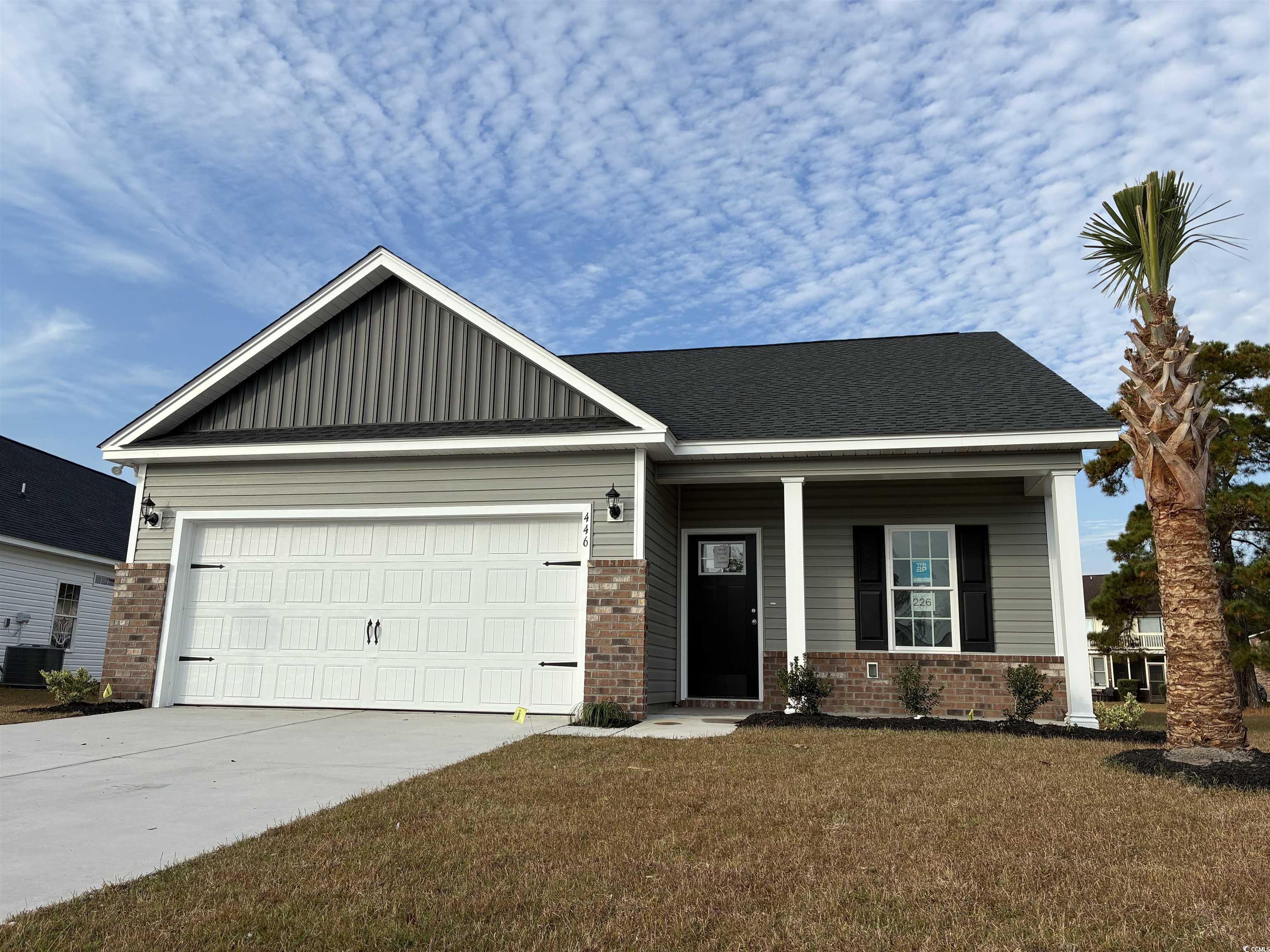 Craftsman house with brick siding, covered porch, driveway, a garage, and a front lawn