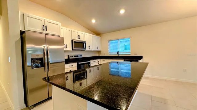 a kitchen with stainless steel appliances granite countertop a sink a stove and a refrigerator