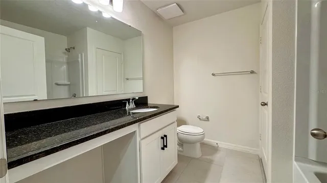 a bathroom with a granite countertop sink and a toilet