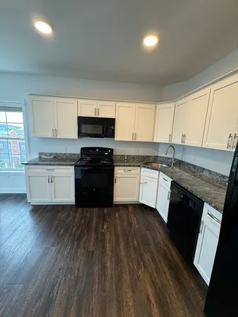 a kitchen with granite countertop a stove top oven sink and cabinets