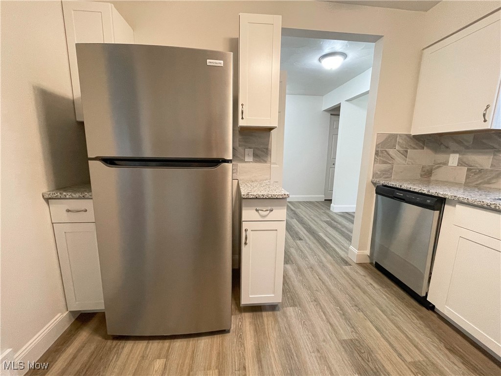 4949 East Radio Road Youngstown, OH 44515 - Photo 13 of 37 Kitchen featuring white cabinets, light hardwood / wood-style floors, stainless steel appliances, and tasteful backsplash