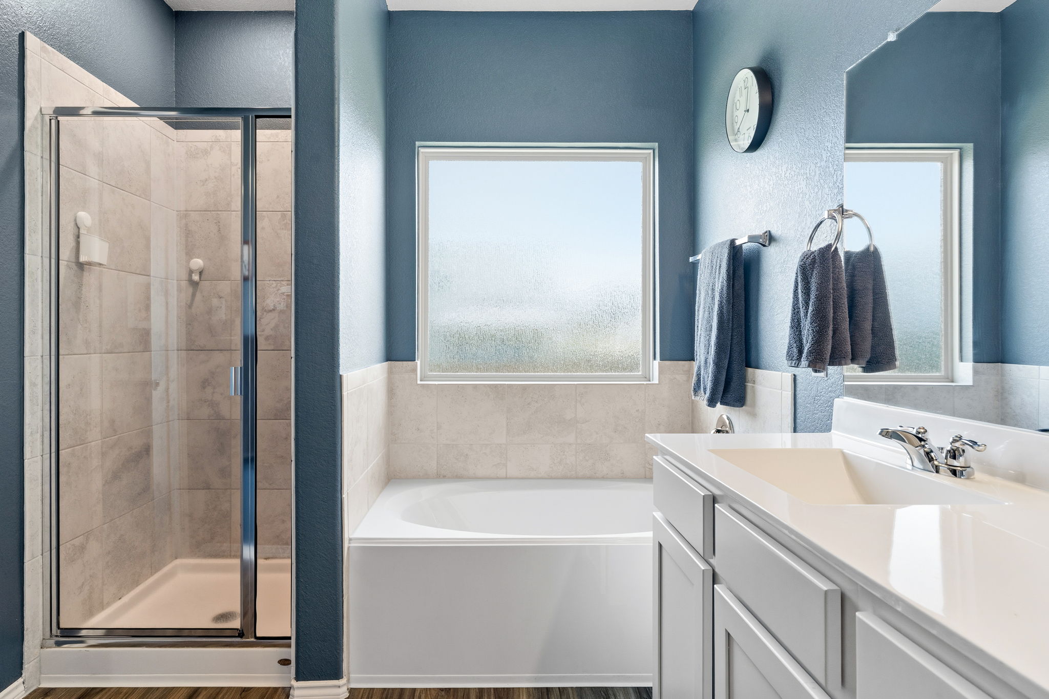 3101 Fresh Spring Road Pflugerville, TX 78660 - Photo 16 of 39 Bathroom featuring a glass-enclosed shower with tile surround, a deep soaking tub, a dual vanity with integrated sinks, and the same luxury vinyl plank found in the living areas.
