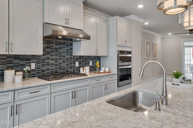 a large kitchen with stainless steel appliances kitchen island a large counter top and wooden floors