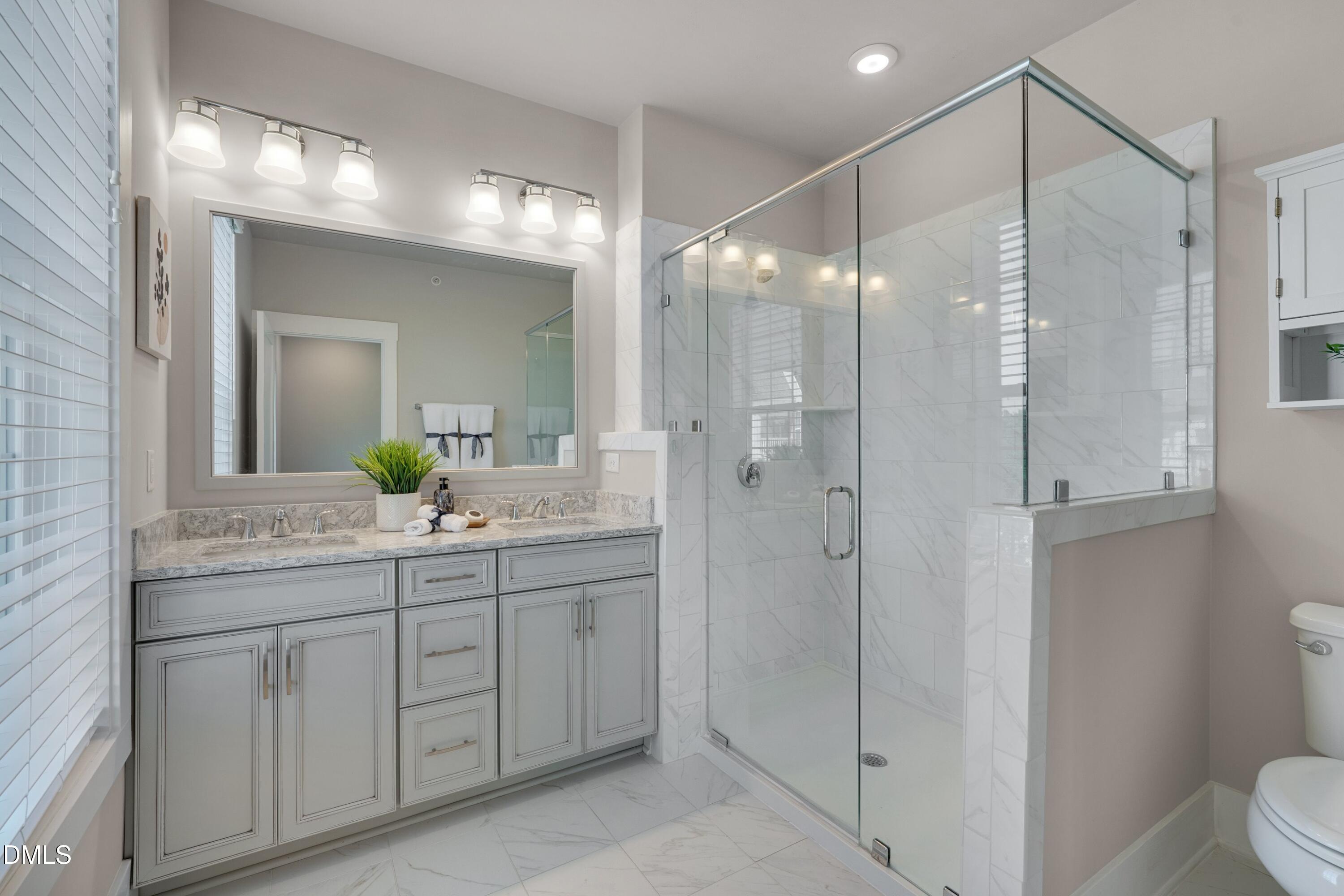 10330 Sablewood Drive, Unit 104 Raleigh, NC 27617 - Photo 13 of 39 a bathroom with a shower sink vanity and mirror