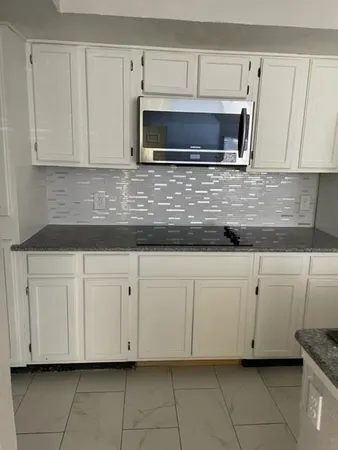 a kitchen with white cabinets and a stove