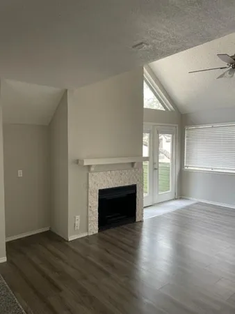 an empty room with wooden floor fireplace and windows