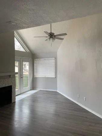 an empty room with wooden floor fireplace and windows