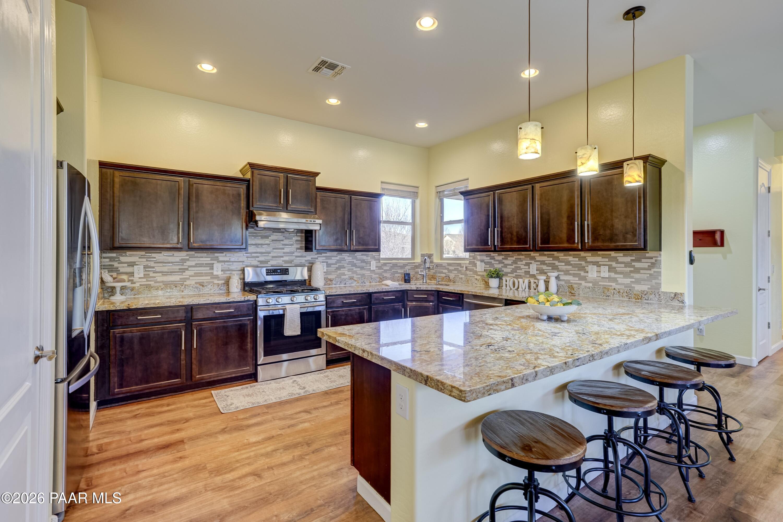 7106 East Prairie Ridge Road Prescott Valley, AZ 86315 - Photo 2 of 27 a kitchen with stainless steel appliances granite countertop a sink counter space and cabinets