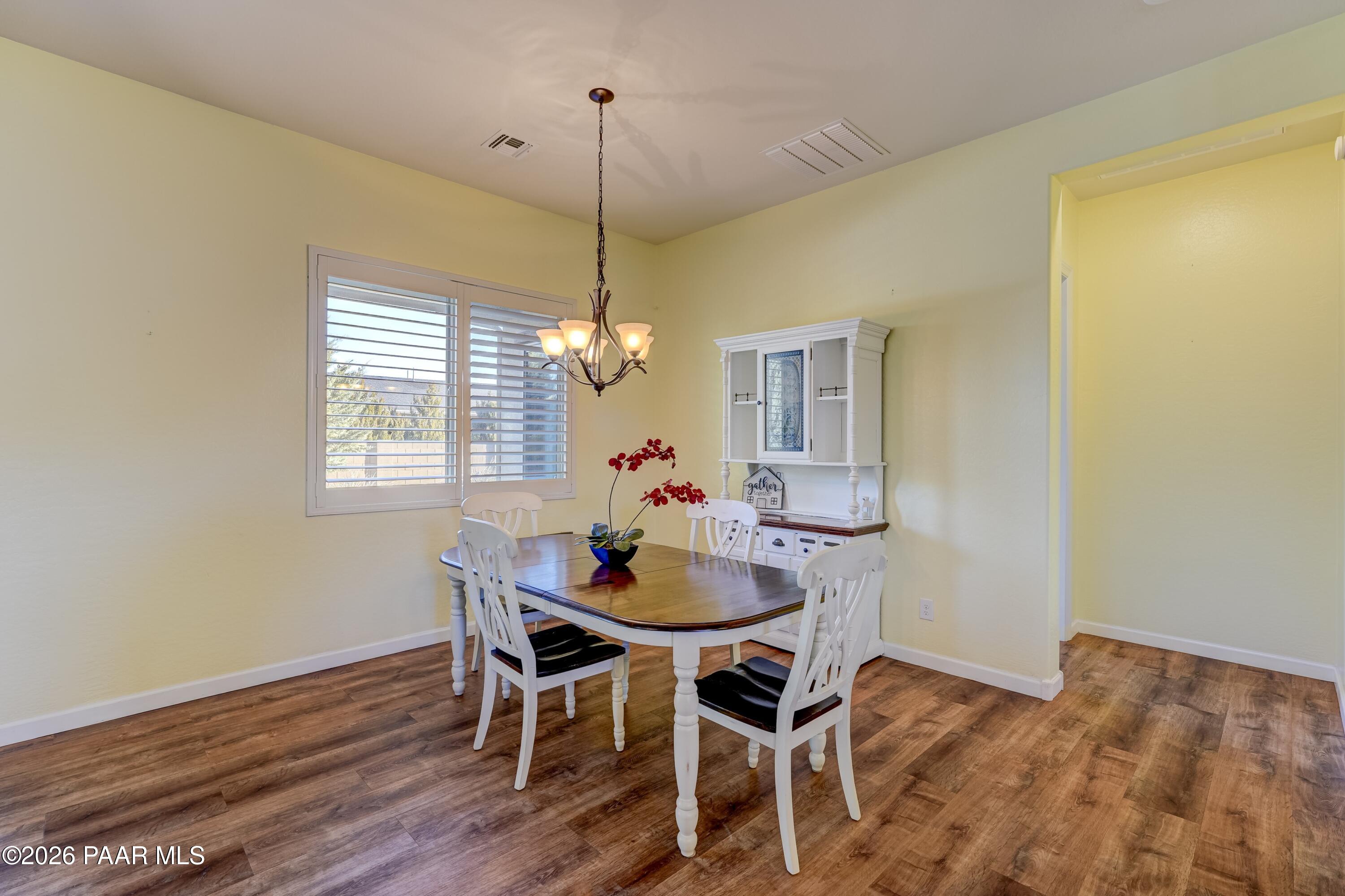 7106 East Prairie Ridge Road Prescott Valley, AZ 86315 - Photo 10 of 27 a dining room with furniture a chandelier and wooden floor