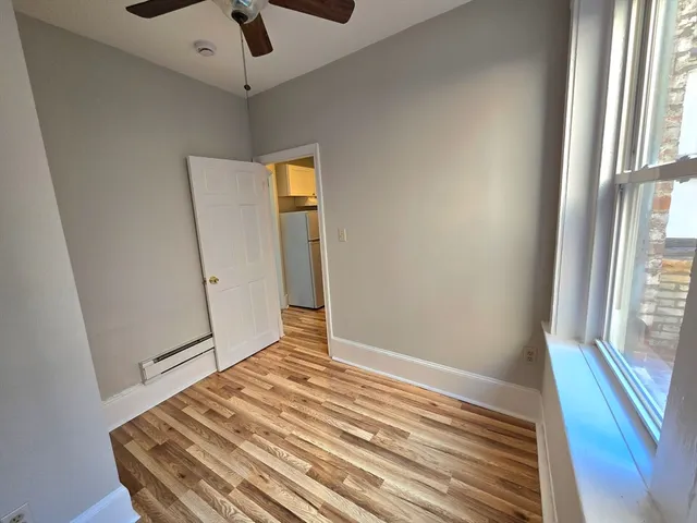 a view of a room with wooden floor and a ceiling fan