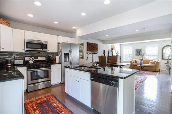 a kitchen with kitchen island granite countertop a stove top oven a sink a dining table and chairs