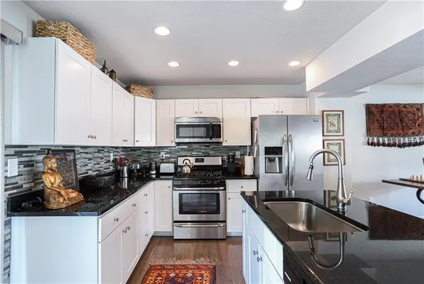 a kitchen with granite countertop a sink stainless steel appliances and cabinets