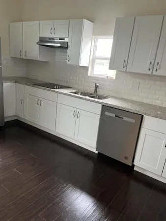a kitchen with granite countertop white cabinets and a wooden floor