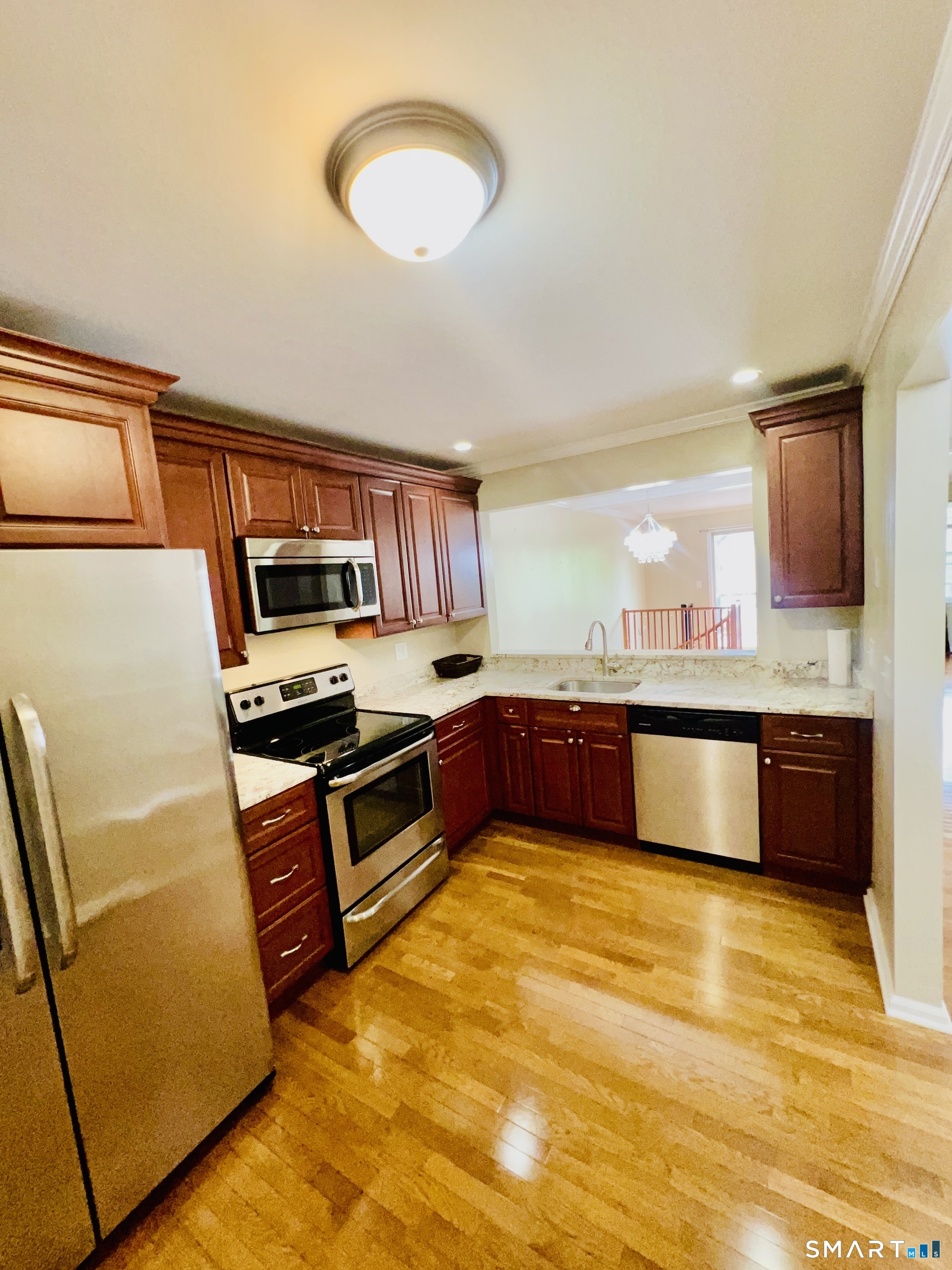 a large kitchen with stainless steel appliances a large counter top a stove a sink and a refrigerator