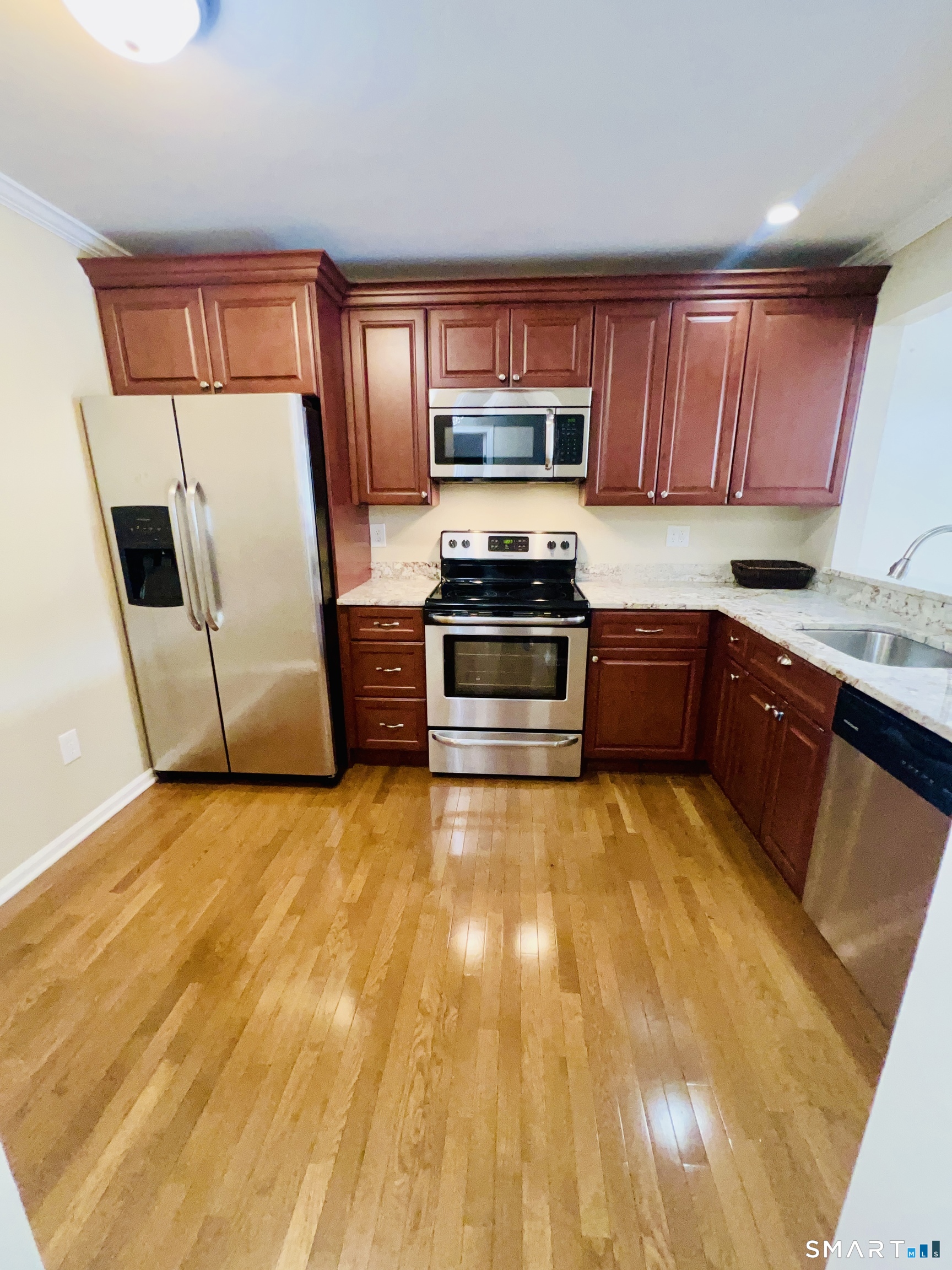 55 Mill Plain Road, Unit 297 Danbury, CT 06811 - Photo 2 of 8 a kitchen with stainless steel appliances granite countertop a stove a sink dishwasher a refrigerator and a microwave with wooden floor