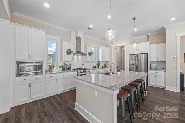 a kitchen with stainless steel appliances granite countertop a kitchen island hardwood floor sink stove and white cabinets