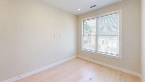 an empty room with wooden floor and windows