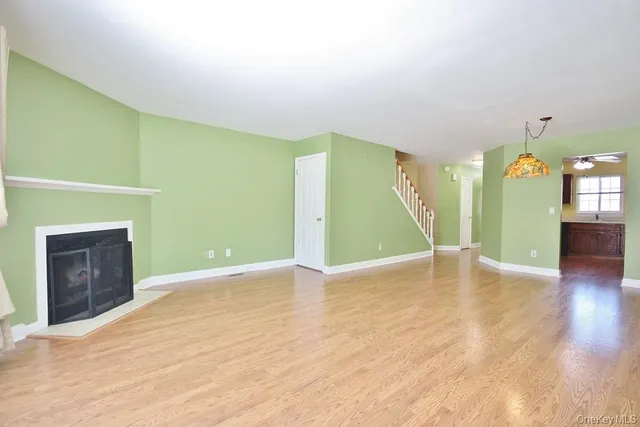 a view of an empty room with window and wooden floor
