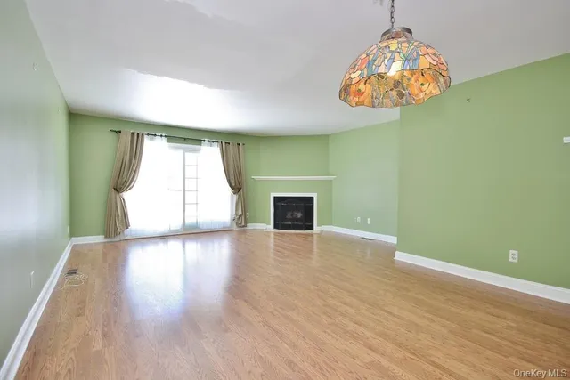 an empty room with wooden floor chandelier and windows