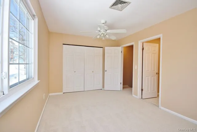 an empty room with windows and fan