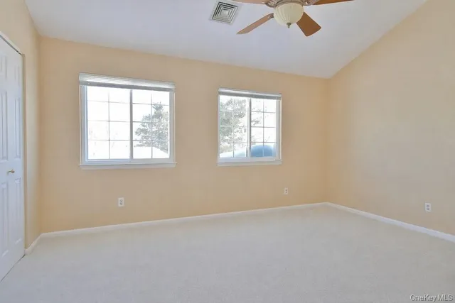 an empty room with chandelier fan and windows