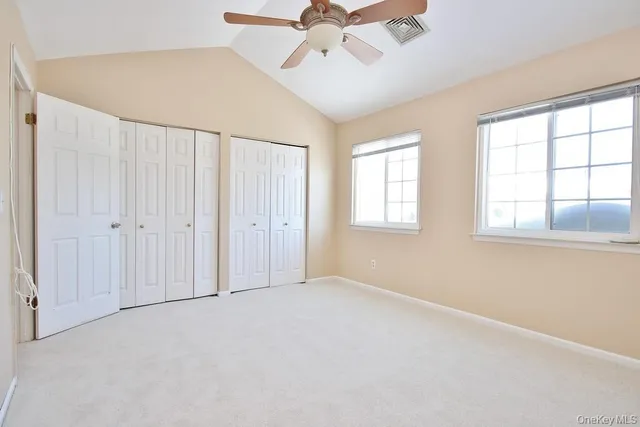 an empty room with chandelier fan and windows