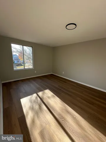 a view of an empty room with wooden floor and windows