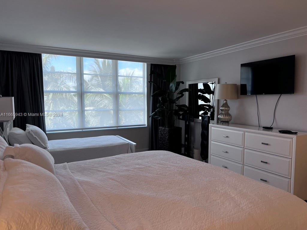 5161 Collins Avenue, Unit 505 Miami Beach, FL 33140 - Photo 23 of 31 a bedroom with a large bed and a flat tv screen on dresser