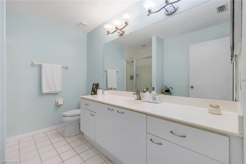 7767 Jewel Lane, Unit 203 Naples, FL 34109 - Photo 13 of 29 a bathroom with a toilet sink and mirror