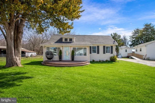 a view of a house with a yard deck and a large tree