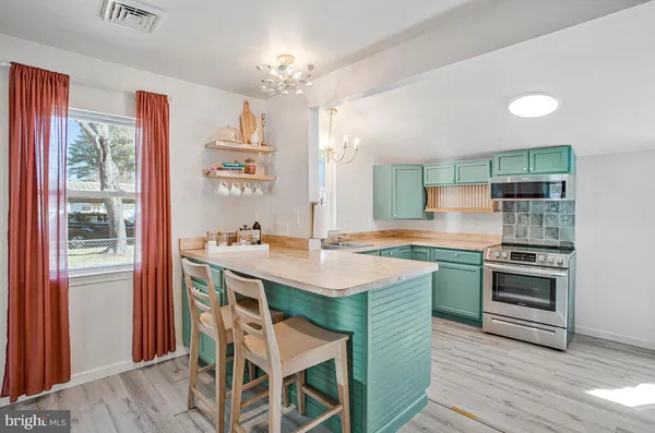 a kitchen with a stove a sink dishwasher a kitchen island with wooden cabinets and floor