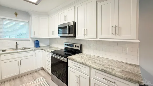 a kitchen with granite countertop white cabinets and white appliances