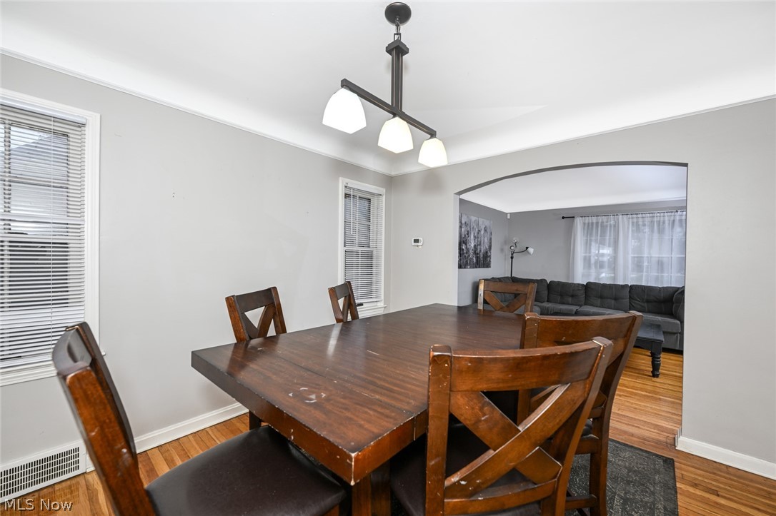 3699 Bainbridge Road Cleveland Heights, OH 44118 - Photo 11 of 37 Dining area featuring wood-finish flooring, a contemporary linear chandelier, and light gray wall tones
