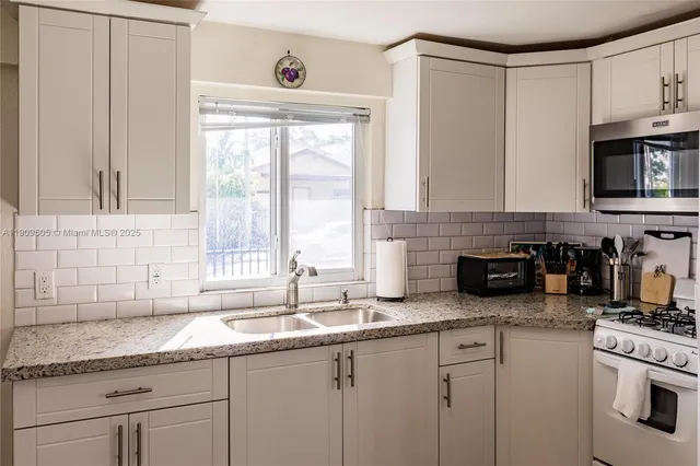 a kitchen with granite countertop a sink a stove and cabinets