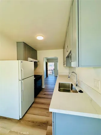 a white kitchen with a sink a refrigerator and a stove