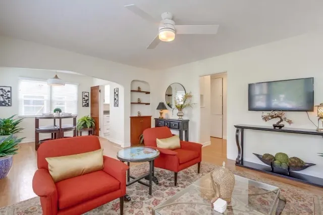 a living room with furniture and a dining table with wooden floor