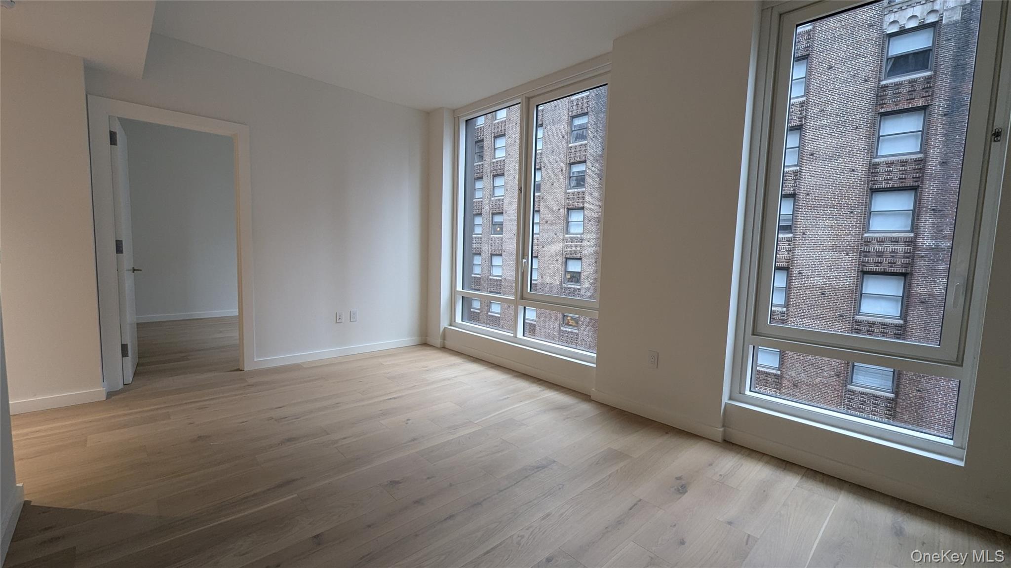 135 East 47th Street, Unit 21A Manhattan, NY 10017 - Photo 3 of 21 a view of an empty room with glass door and wooden floor