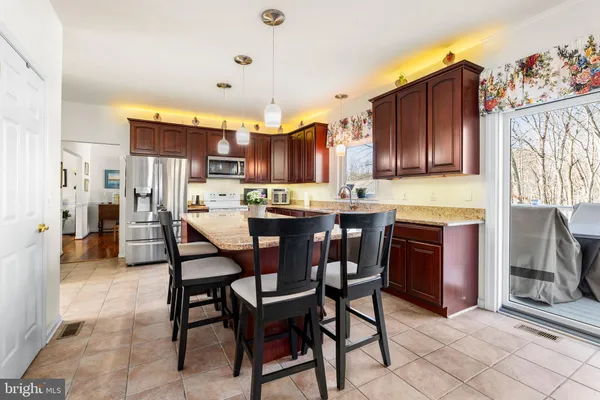 a kitchen with stainless steel appliances kitchen island granite countertop a table chairs and a refrigerator
