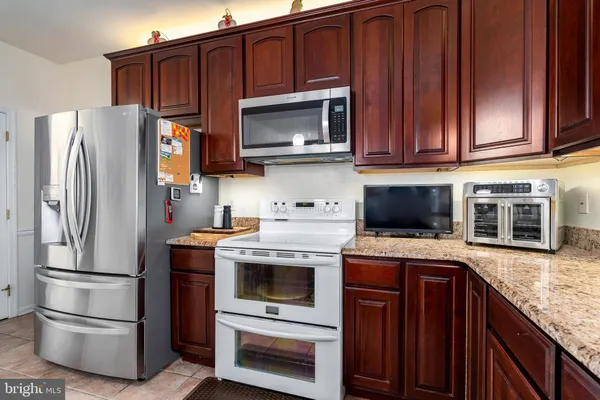 a kitchen with granite countertop a refrigerator stove and microwave