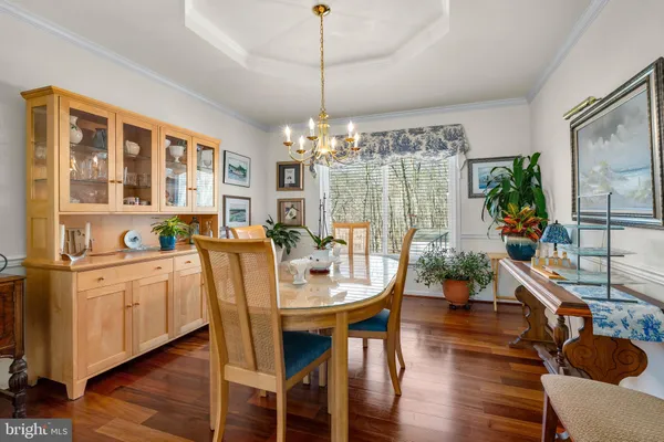 a dining room with furniture a chandelier and wooden floor