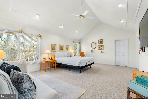 a spacious bedroom with a bed a table and potted plant with the dresser